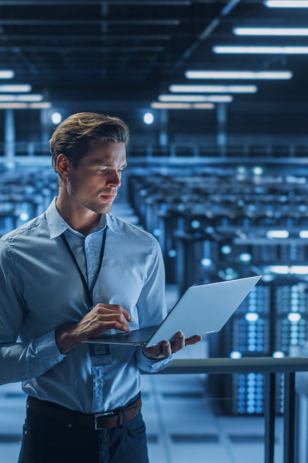 IT security specialist holding a laptop inside a server facility